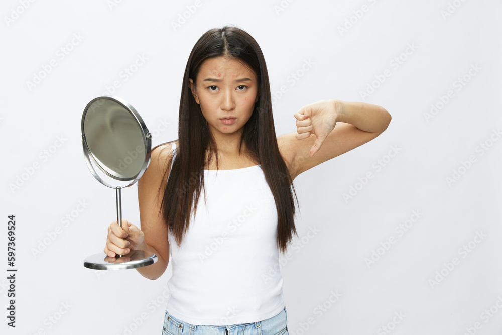 Asian woman with mirror in hand facial skin problems, acne and inflammation, red rash and allergies, chicken pox, sadness from rashes. Facial skin care concept for diseases and nerves Asian woman with mirror in hand facial skin problems, acne and inflammation, red rash and allergies, chicken pox, sadness from rashes. Facial skin care concept for diseases and nerves