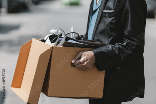 Businessman fired or resign from the company are carrying boxes down the street looking for a new job. Unemployed, hiring job, quitting job concept..