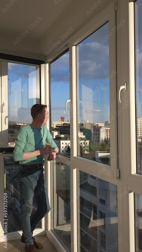 Man goes to balcony of his apartment in high-rise building Man goes to balcony of his apartment in high-rise building