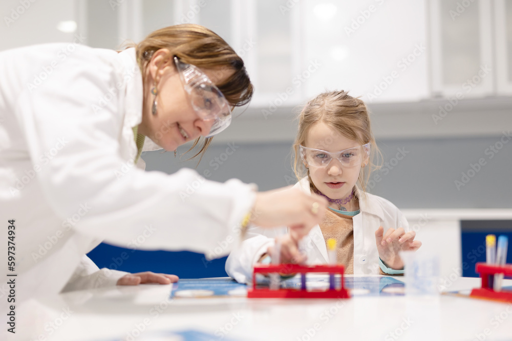 Young student works girl in laboratory with help of teacher in school Young student works girl in laboratory with help of teacher in school
