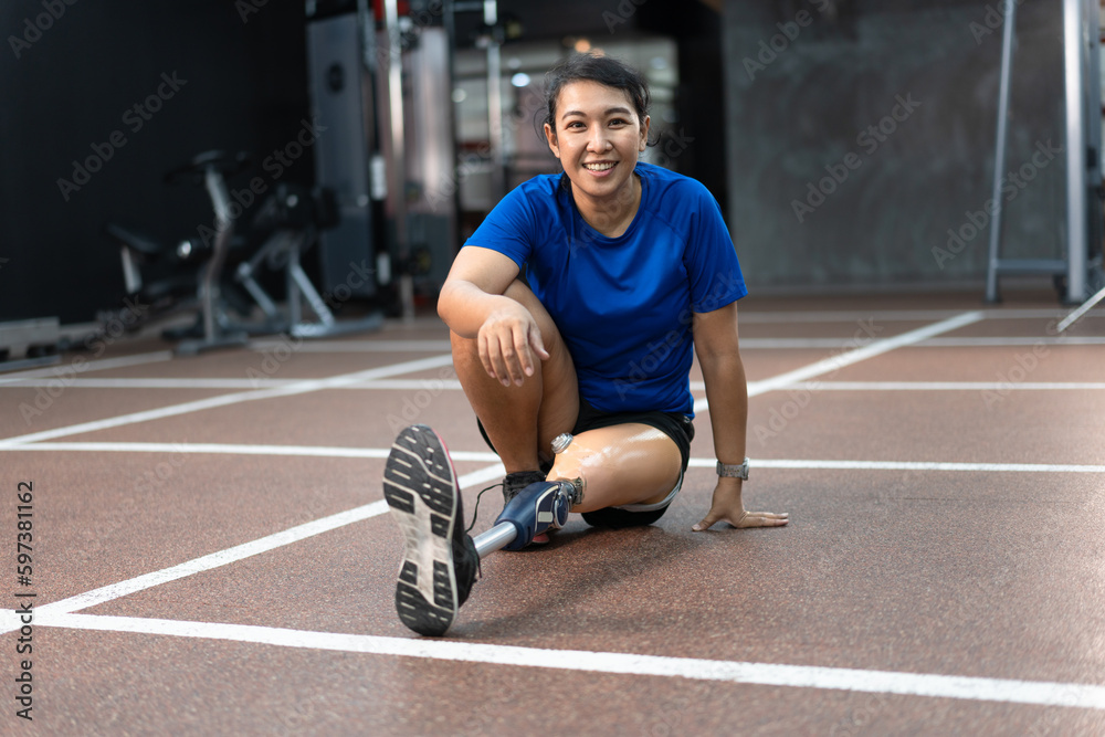 Asia woman smiling with prosthetic leg exercise at gym or fitness	
