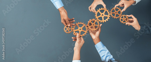Fotografia Panoramic shot top view of business people holding cog wheel as unity and teamwork in corporate workplace concept