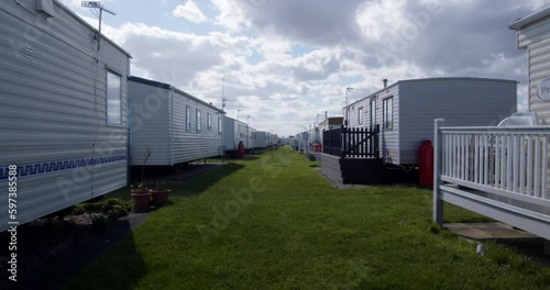 outside shot of static caravans on both sides, in a caravan park with sun coming out from behind the clouds photo