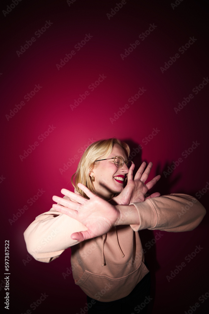 A cheerful woman dancing and having fun isolated on magenta background. Viva magenta, color of the year.