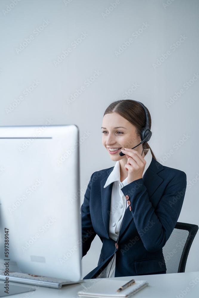 Serious call center operator in wireless headset talking to customer, woman in headphones with microphone consulting customer on phone in customer support service, looking at computer screen. Serious call center operator in wireless headset talking to customer, woman in headphones with microphone consulting customer on phone in customer support service, looking at computer screen.