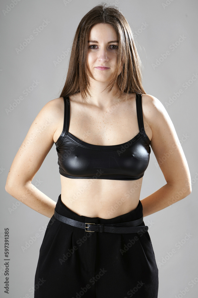 Beautiful young woman posing in a black latex or leather top in photo studio Beautiful young woman posing in a black latex or leather top in photo studio