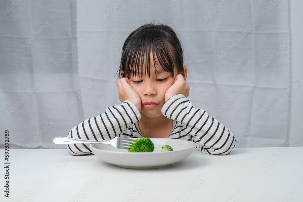 Foto de Children don't like to eat vegetables. Cute Asian girl refusing ...