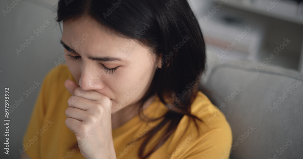 Young Asian woman suffering from flu, coughing and sneezing at home Young Asian woman suffering from flu, coughing and sneezing at home