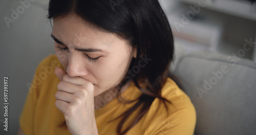 Young Asian woman suffering from flu, coughing and sneezing at home