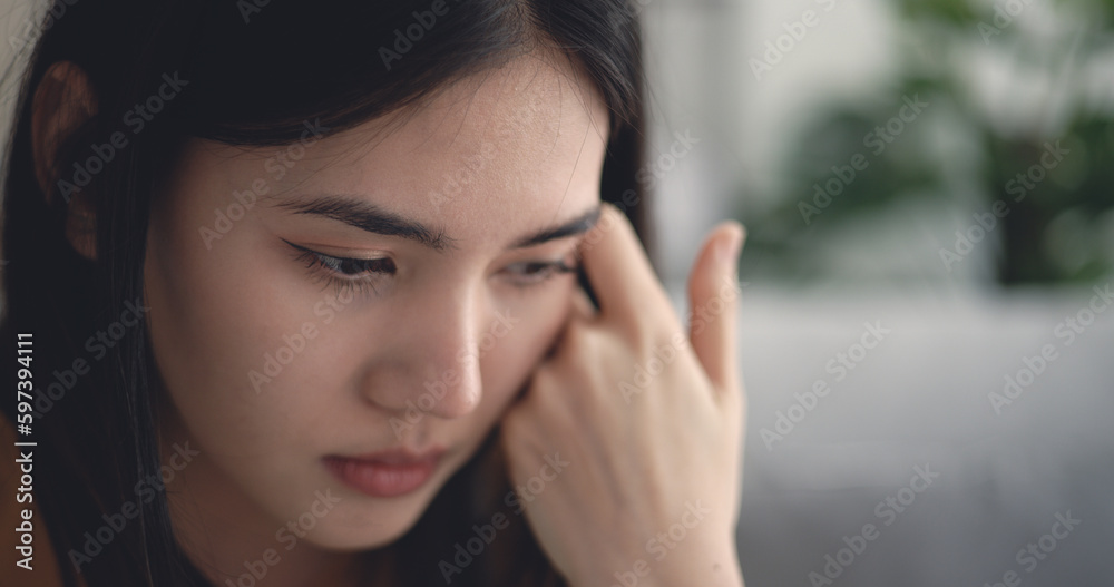 Young asian woman sitting on sofa so thoughtful and sadness in living room Young asian woman sitting on sofa so thoughtful and sadness in living room