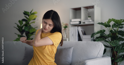 Young Asian woman shoulder pain in the living room at home.