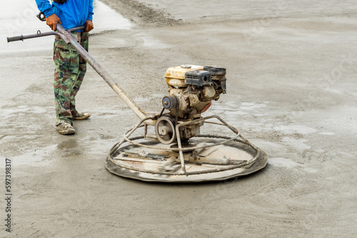 Construction worker is trowelling and finishing wet concrete with special construction equipment. Float blades. For smoothing and polishing concrete, concrete floors machine grinding by power trowel