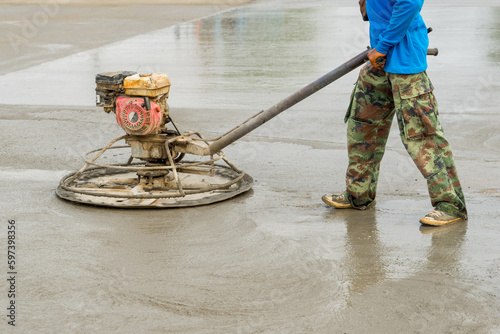 Construction worker is trowelling and finishing wet concrete with special construction equipment. Float blades. For smoothing and polishing concrete, concrete floors machine grinding by power trowel