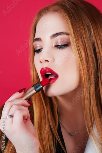 Young beautiful woman paints her lips with lipstick.