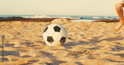 Child playing football on the beach, family fun outdoors players in soccer in dynamic action have fun playing football in summer day under sunlight.