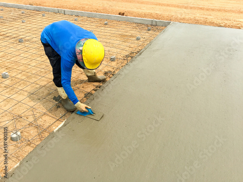 A worker adjusts levels of concrete in formwork using a trowel. For smoothing and polishing concrete slab.