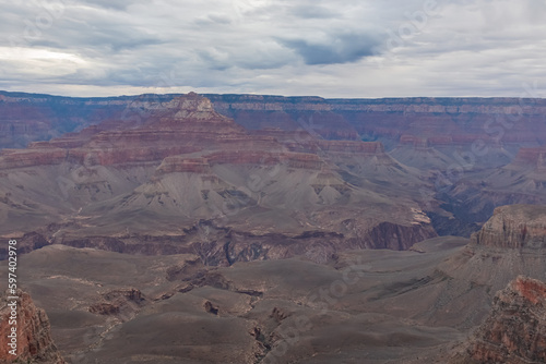 Panoramic aerial view from South Kaibab hiking trail at South Rim of Grand Canyon National Park, Arizona, USA, America. Colorado River weaving through valleys and rugged terrain. Clouds and overcast.