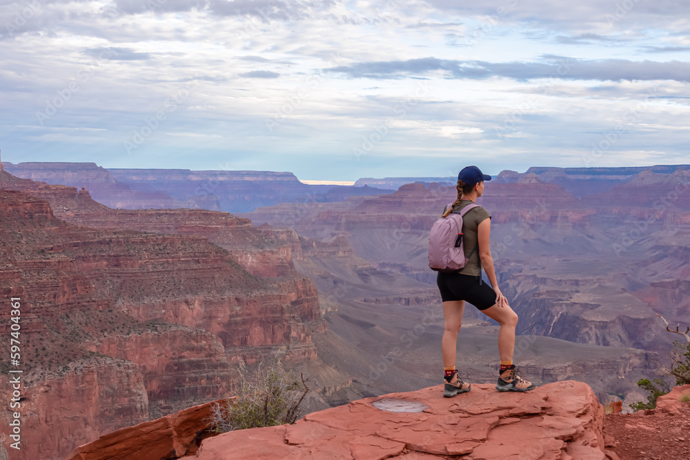 Woman with scenic view from Ooh Ahh point on South Kaibab hiking trail at South Rim, Grand Canyon National Park, Arizona, USA. Colorado River weaving through valleys and rugged terrain. O Neill Butte