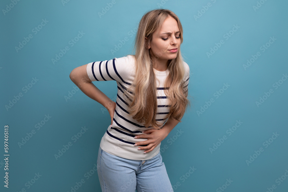 upset girl holding her stomach because of illness on a blue isolated background upset girl holding her stomach because of illness on a blue isolated background