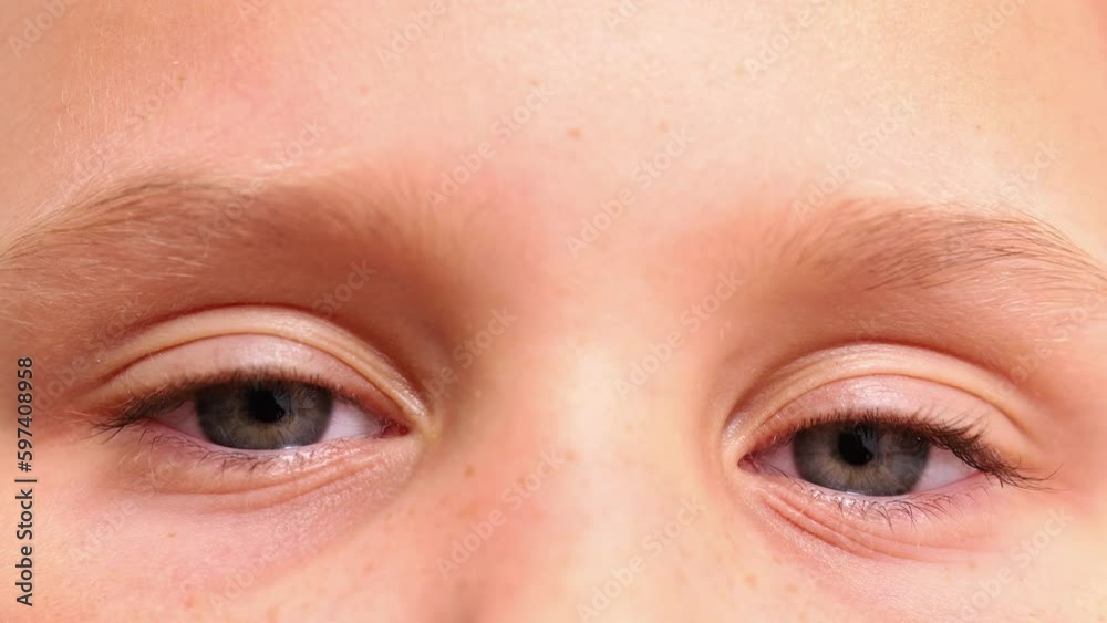 Close up video of cropped child blue eyes blinking slowly and looking