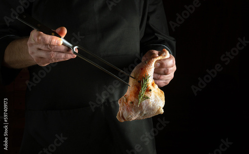 The cook prepares a chicken leg in the restaurant kitchen. Preparing raw meat for grilling in the chef hand