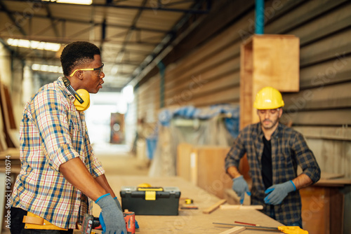 Two Carpenter working on wood craft at workshop to produce construction material or wooden furniture. The young carpenter use professional tools for crafting. DIY maker and carpentry work concept.