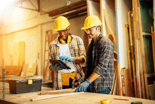 Two Carpenter working on wood craft at workshop to produce construction material or wooden furniture. The young carpenter use professional tools for crafting. DIY maker and carpentry work concept.