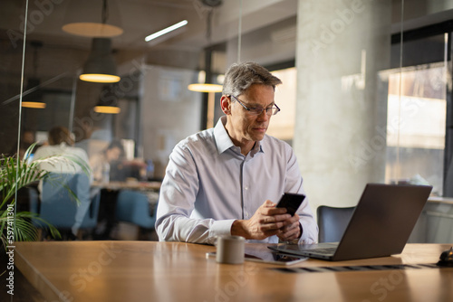 Businessman in office. Handsome man using the phone at work