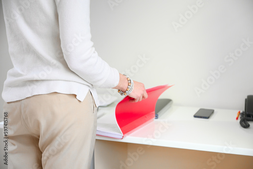 Back view of a confident and sophisticated woman with wears a creamy white sweater in her immaculately organized office. 