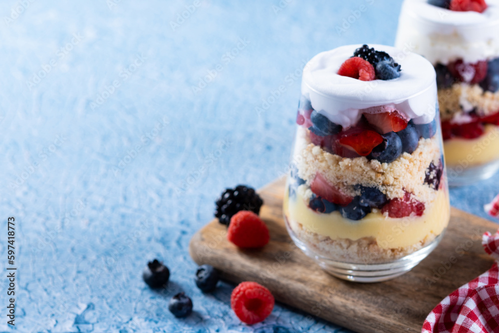 Trifle dessert with berries and cream on blue background. Copy space Trifle dessert with berries and cream on blue background. Copy space