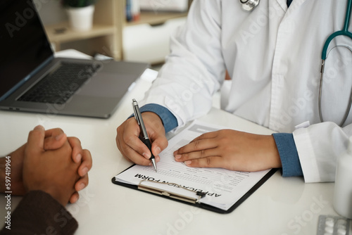 Professional doctors in white medical uniforms talk to discuss results or symptoms and advise male patients and sign medical documents at clinic appointments.