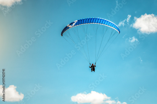 Paraglider wing flying in blue cloudless sky