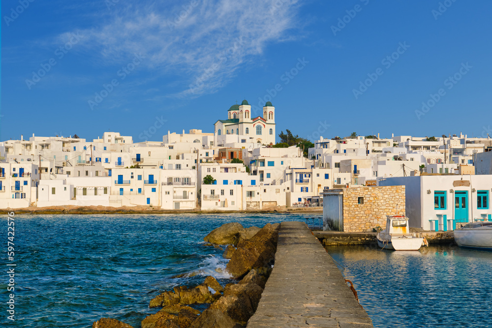 Greek whitewashed houses and church by harbour watersfront on sunny