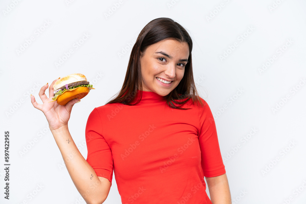 Young caucasian woman holding a burger isolated on white background smiling a lot Young caucasian woman holding a burger isolated on white background smiling a lot