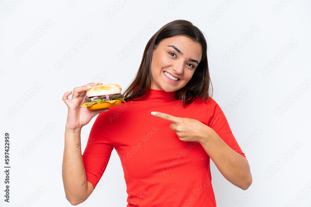 Young caucasian woman holding a burger isolated on white background and pointing it Young caucasian woman holding a burger isolated on white background and pointing it