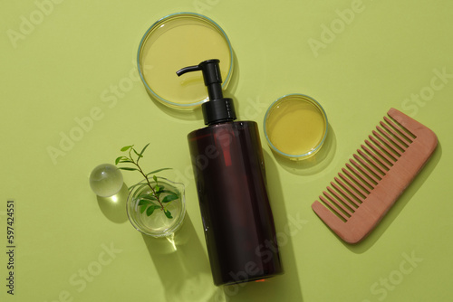 Cosmetic amber bottle unlabeled containers shampoo on green background with glassware containing essence, green leaf and comb. Mockup for design photo