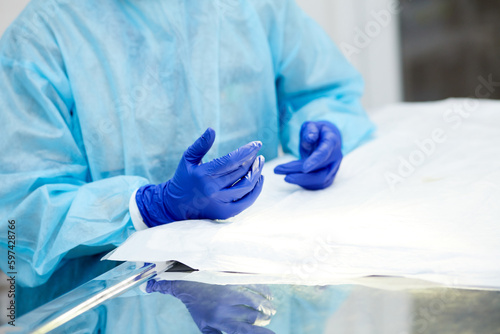Doctor's, surgeon's hands holding professional medical tools. Doctor wearing protective gloves and apron. Concept of medicine, hospital, healthcare, treatment, profession