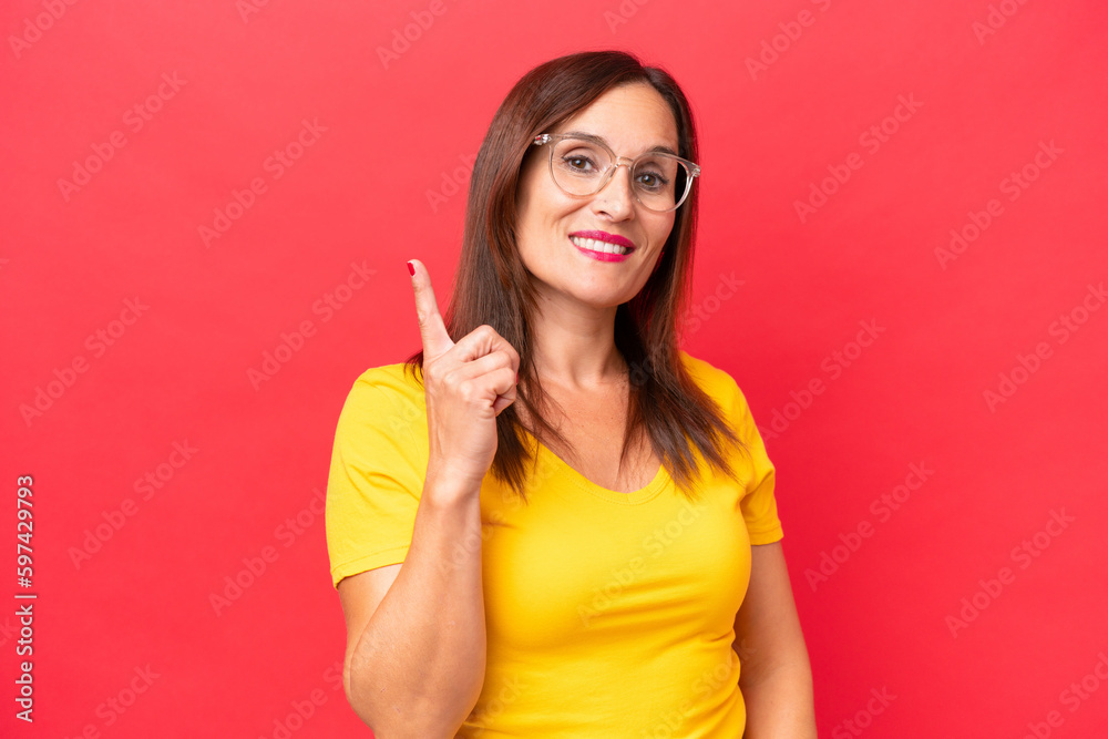 Middle-aged caucasian woman isolated on red background showing and lifting a finger in sign of the best Middle-aged caucasian woman isolated on red background showing and lifting a finger in sign of the best