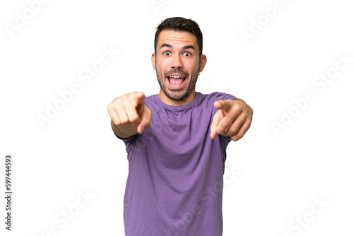 Young handsome caucasian man over isolated background surprised and pointing front