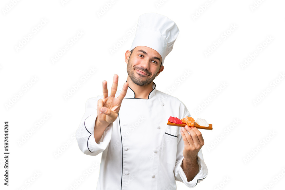 Young caucasian chef holding a sushi over isolated background happy and counting three with fingers Young caucasian chef holding a sushi over isolated background happy and counting three with fingers