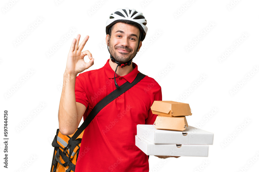Young handsome caucasian man with thermal backpack and holding takeaway food over isolated background showing ok sign with fingers Young handsome caucasian man with thermal backpack and holding takeaway food over isolated background showing ok sign with fingers