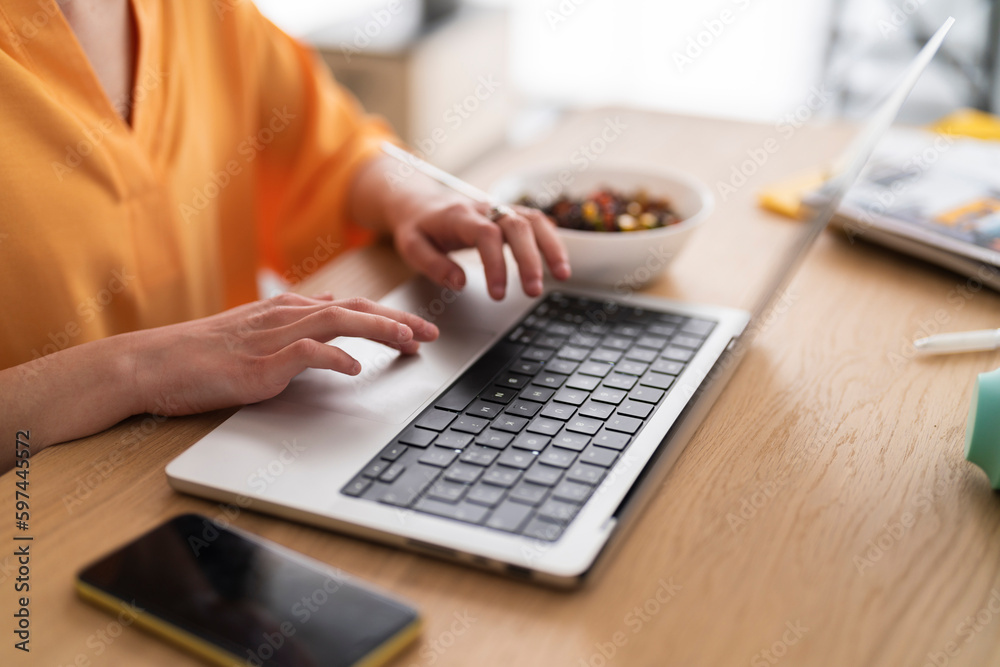 crop anonymous female in casual clothes sitting at table with bowl of healthy vegan salad and working on project on laptop crop anonymous female in casual clothes sitting at table with bowl of healthy vegan salad and working on project on laptop