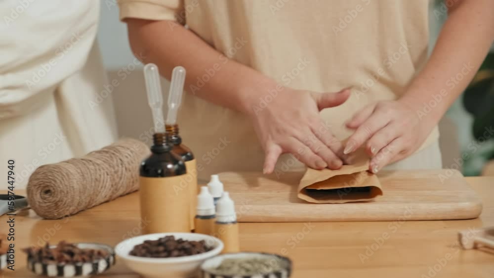 Cropped shot of unrecognizable elegant female hands wrapping handmade soap in craft paper