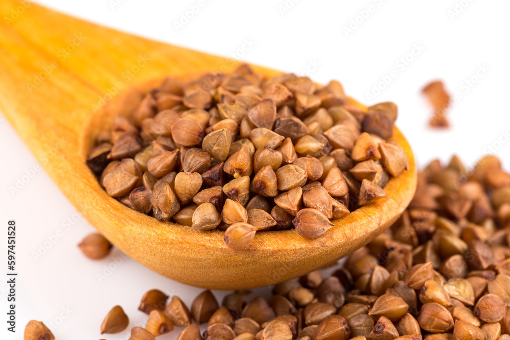 Uncooked buckwheat on wooden spoon