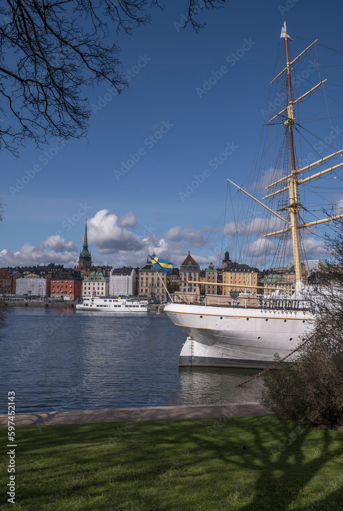 Stern of steal sailing hotel boat, archipelago commuting boat passing the old town Gamla Stan, a sunny spring day with cumulus clouds in Stockholm