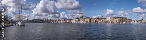Panorama over the bay Strömmen, old town Gamla Stan, the island Skeppsholmen with a steal sailing hotel boat, a sunny spring day with cumulus clouds in Stockholm