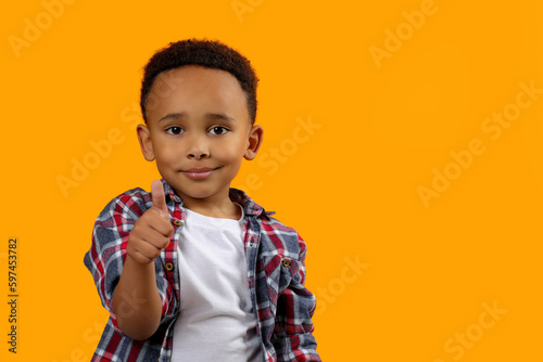 African-American boy showing thumb up on orange background. Space for text