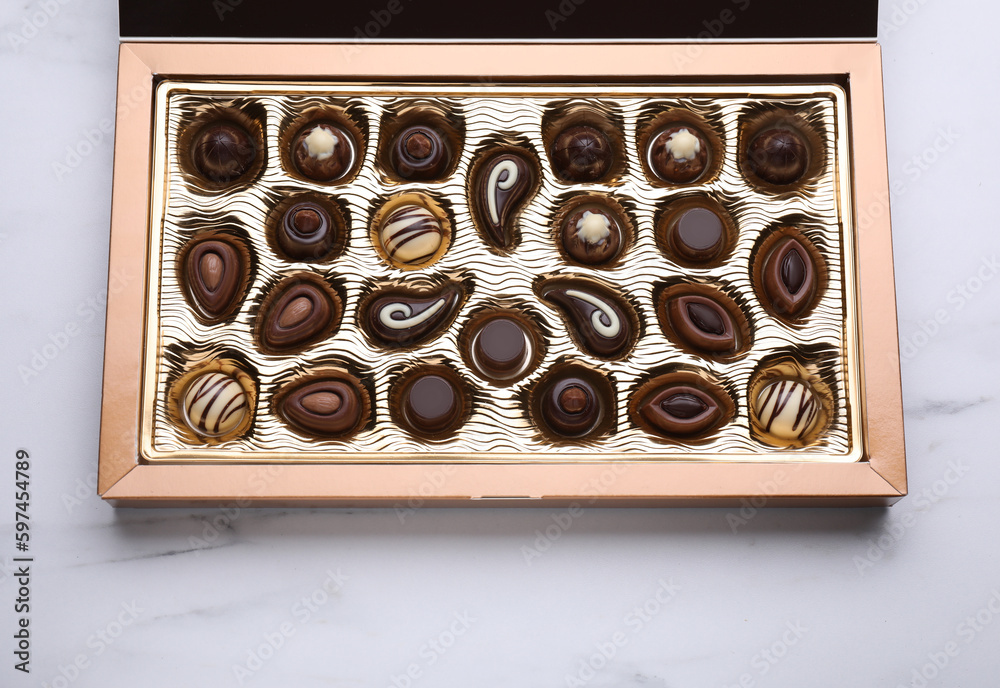 Box of delicious chocolate candies on white marble table, top view Box of delicious chocolate candies on white marble table, top view