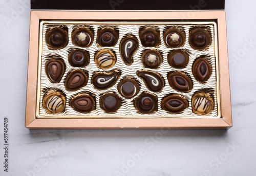 Box of delicious chocolate candies on white marble table, top view