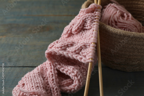 Soft pink woolen yarn, knitting and needles on wooden table, closeup. Space for text